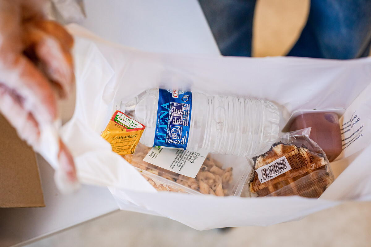 Les bénévoles de l'Armée du Salut préparent les colis alimentaires épaulés par l'agent de sécurité et le logisiticien.